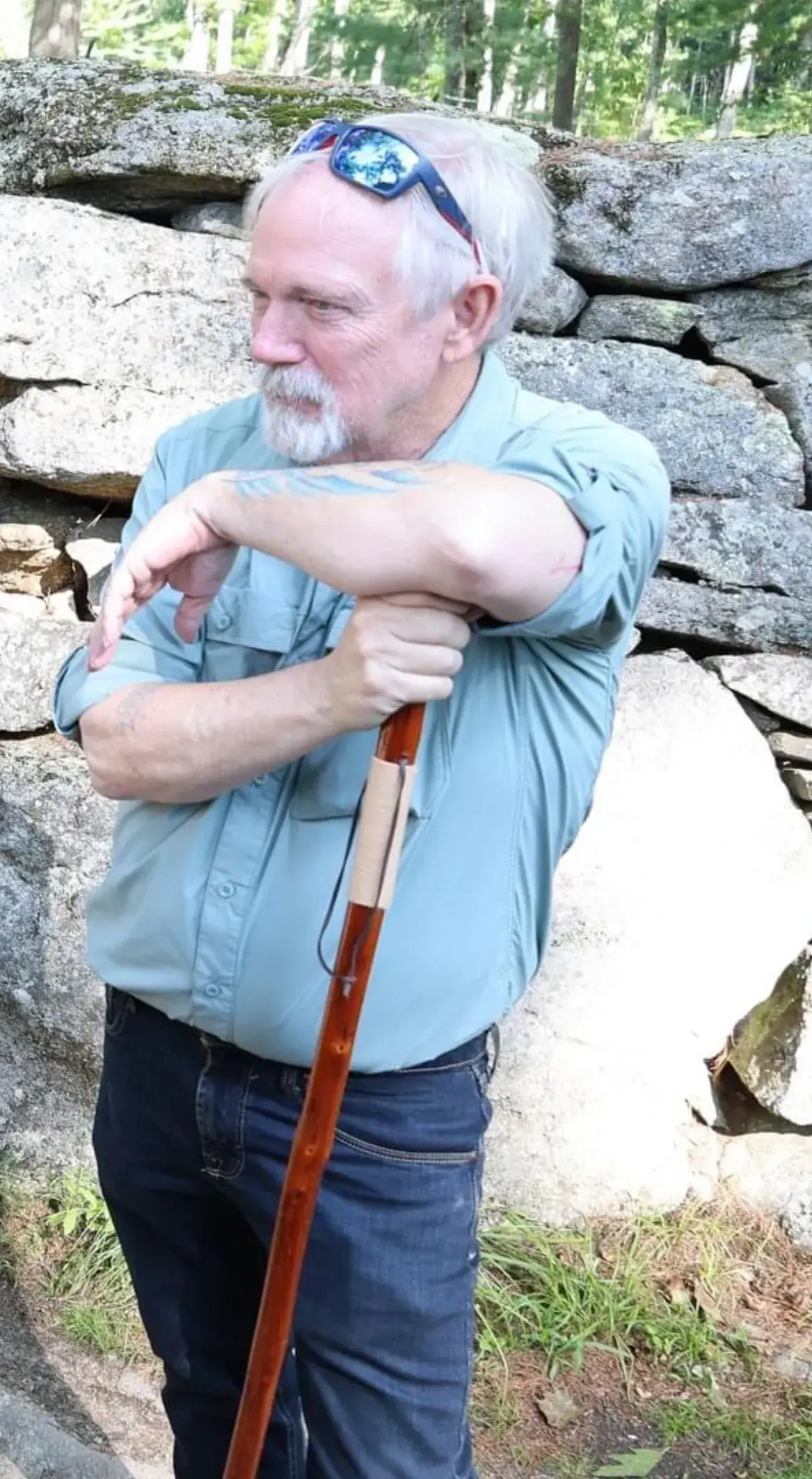 Man with walking stick by stone wall