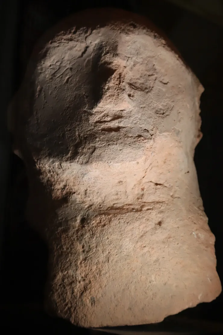 Close-up of an ancient, weathered stone sculpture's face.