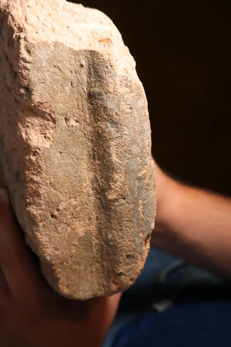 Close-up of a rough, oval-shaped stone tool held in hand.