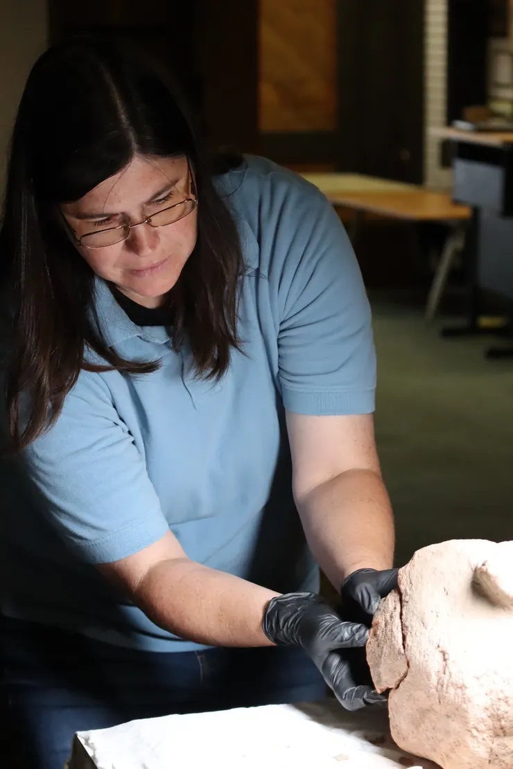 Person in blue shirt examining a dog's paw indoors.